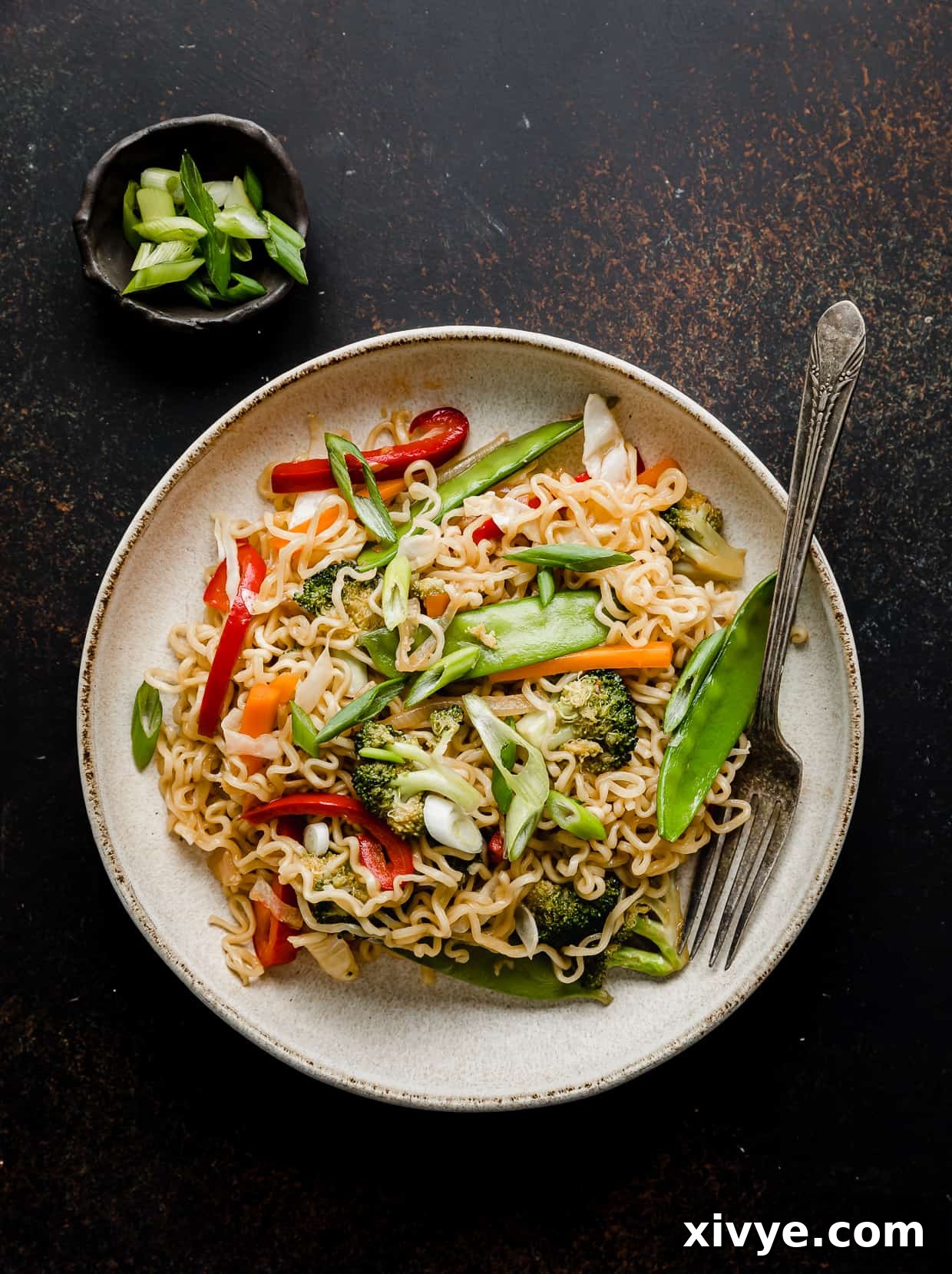 A plate of Ramen with Vegetables on a brown background.