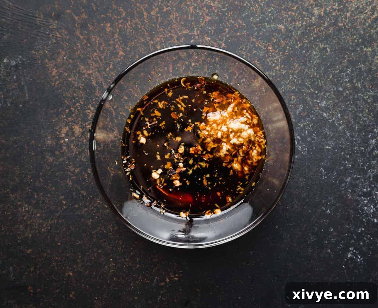 A glass bowl of brown sauce to stir into the stir fry ramen noodles with veggies. 