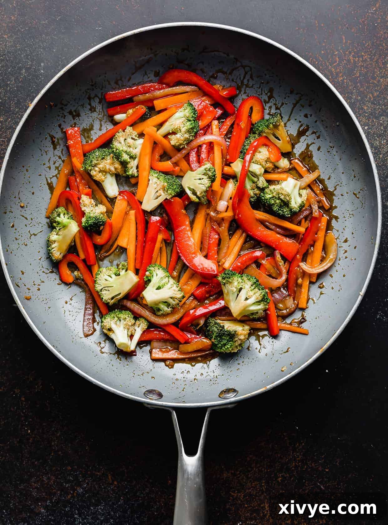 Cooked red peppers, broccoli, and carrots in a skillet.