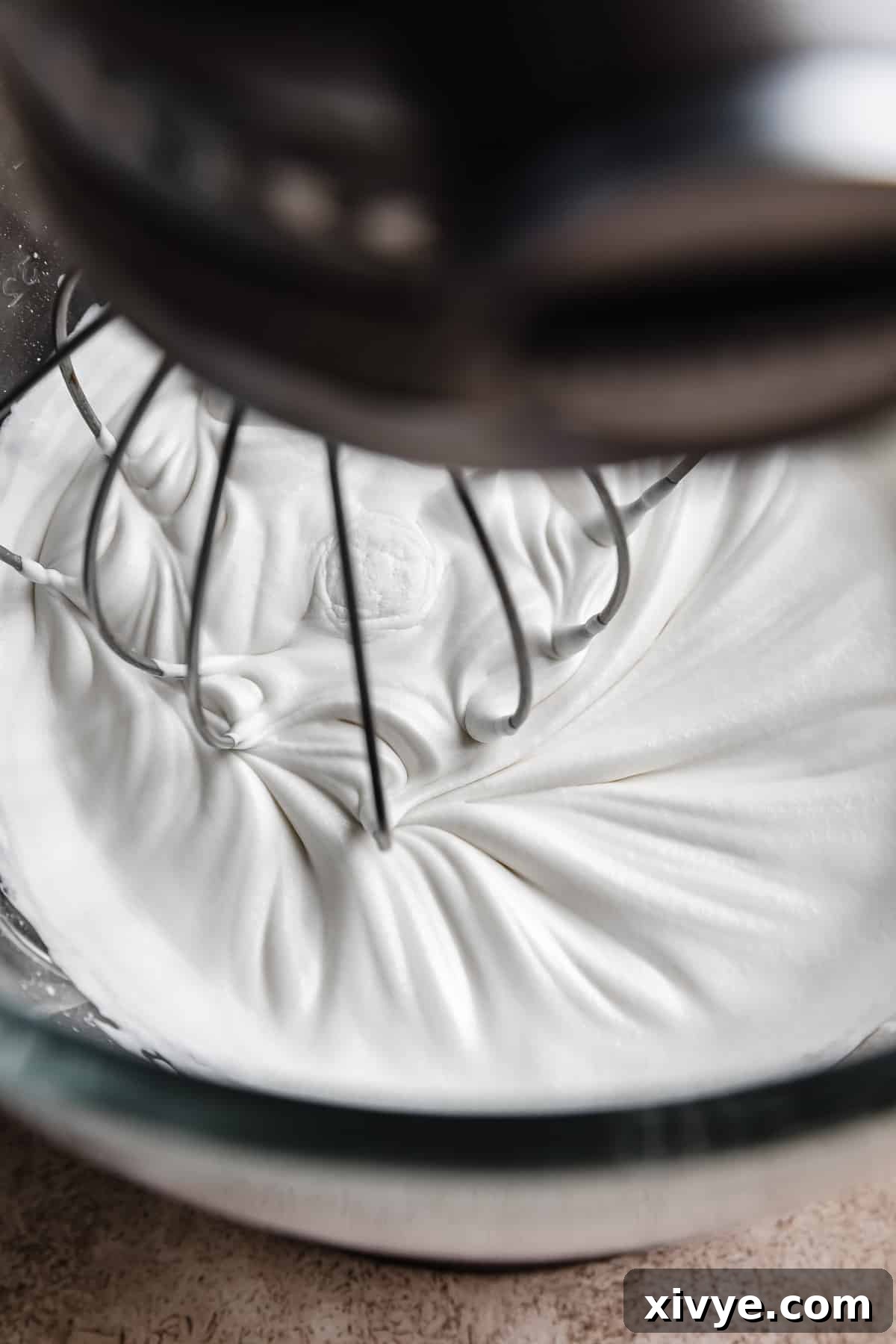 Tangy Greek Yogurt Whip 5 Homemade whipped cream being mixed in a stand mixer bowl with a whisk attachment, demonstrating the stiff peaks forming.