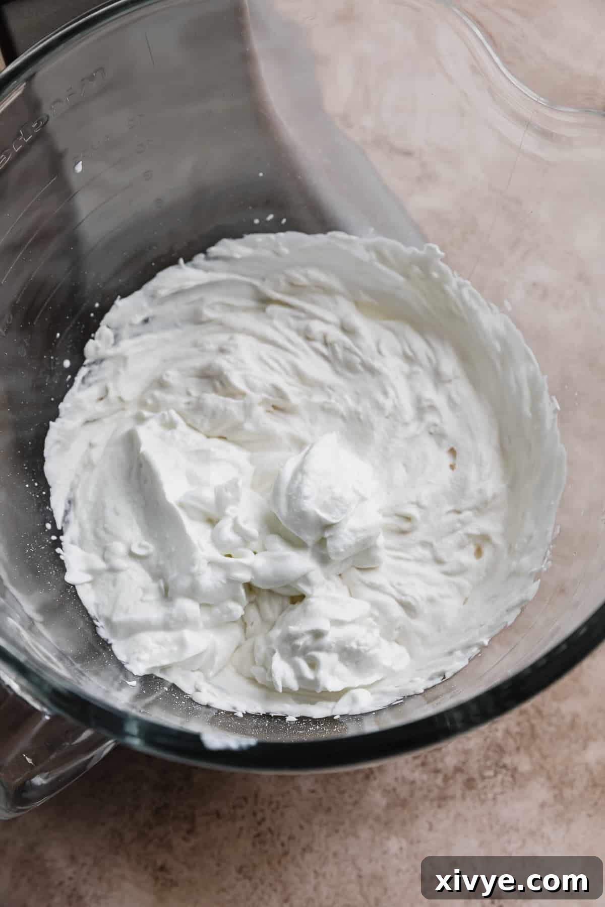 Tangy Greek Yogurt Whip 6 A glass bowl containing a mixture of freshly whipped cream and plain Greek yogurt, showing its combined texture.