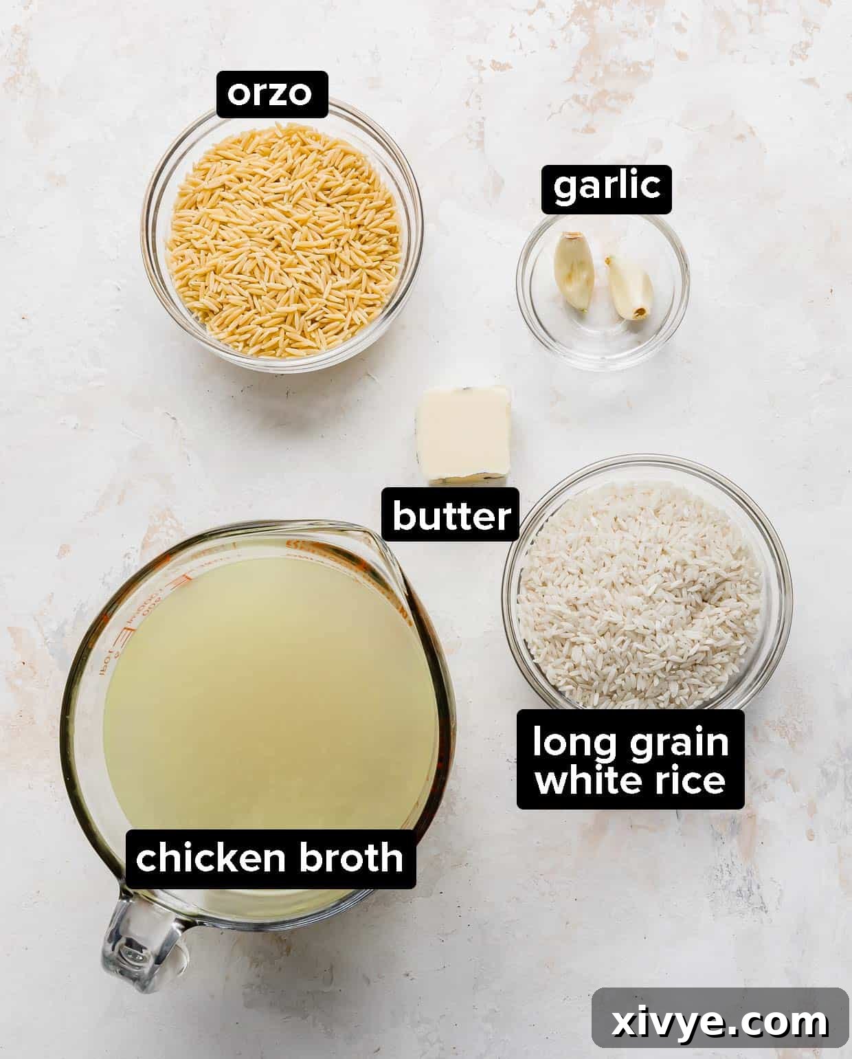 Orzo Pilaf 3 A visual display of the key ingredients required to prepare the Orzo Rice Pilaf: Orzo pasta, white rice, butter, garlic cloves, and chicken broth.