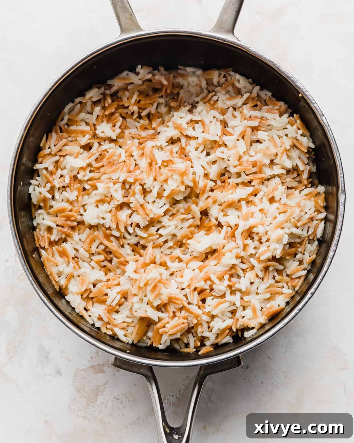Orzo Pilaf 8 The cooked Orzo Rice Pilaf sits fluffed and steamy in the saucepan, indicating it's perfectly done and ready for seasoning.