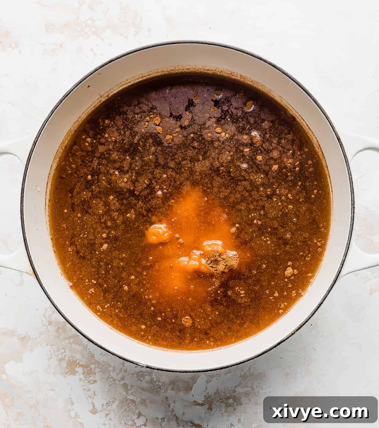 A large white pot full of apple cider, pumpkin puree, brown sugar, and pumpkin pie spice. 