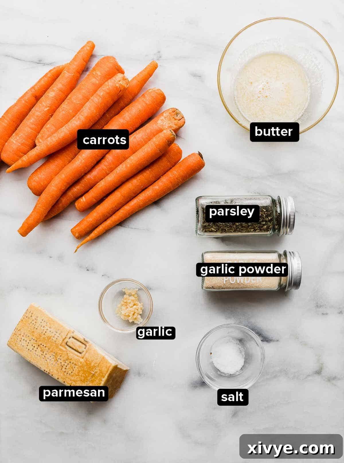 A selection of fresh ingredients laid out on a white surface, including vibrant orange carrots, a stick of butter, garlic cloves, a pinch of salt, a sprig of fresh parsley, and a block of Parmesan cheese, all ready to be transformed into Garlic Butter Roasted Carrots.