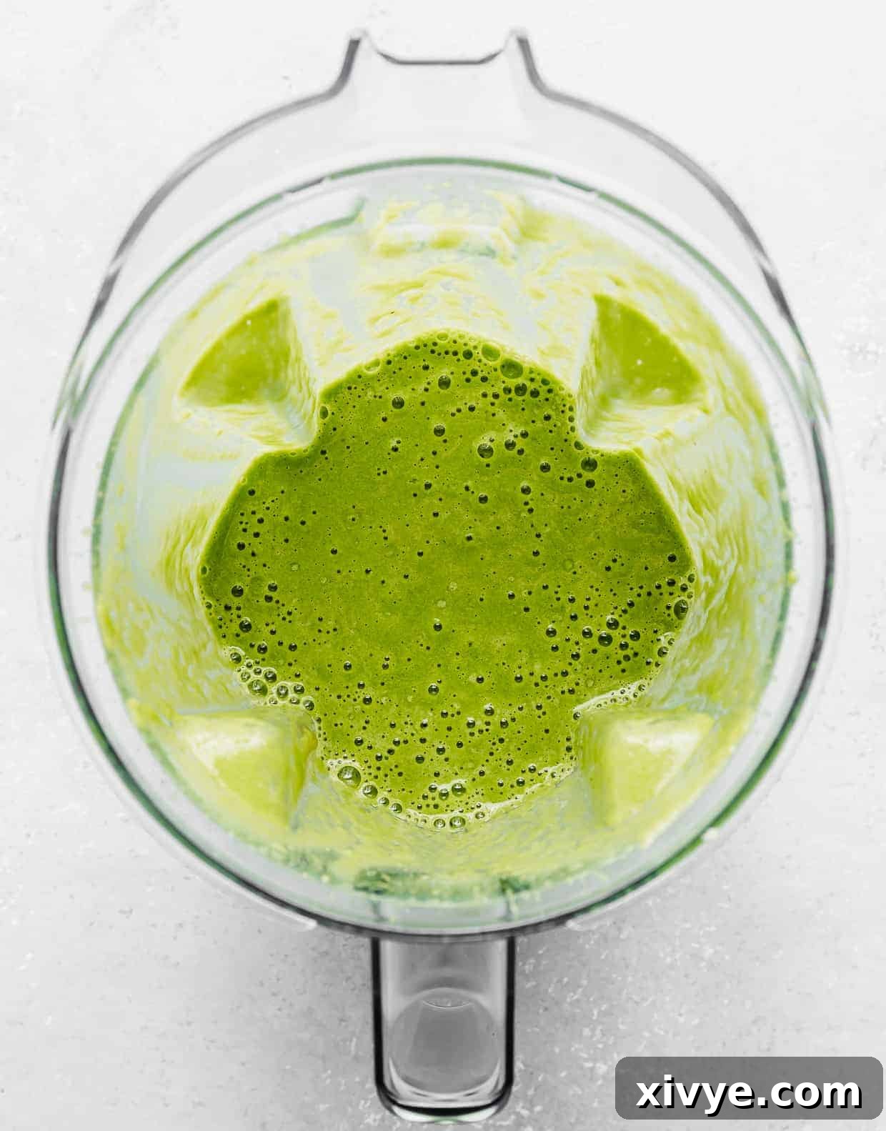 A blender with bright green celery smoothie in it.