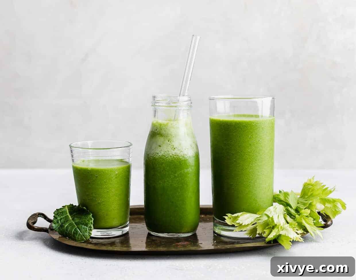 Three glasses full of green celery drink against a white background.