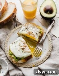 A slice of toasted bread with smashed avocado and egg on it.