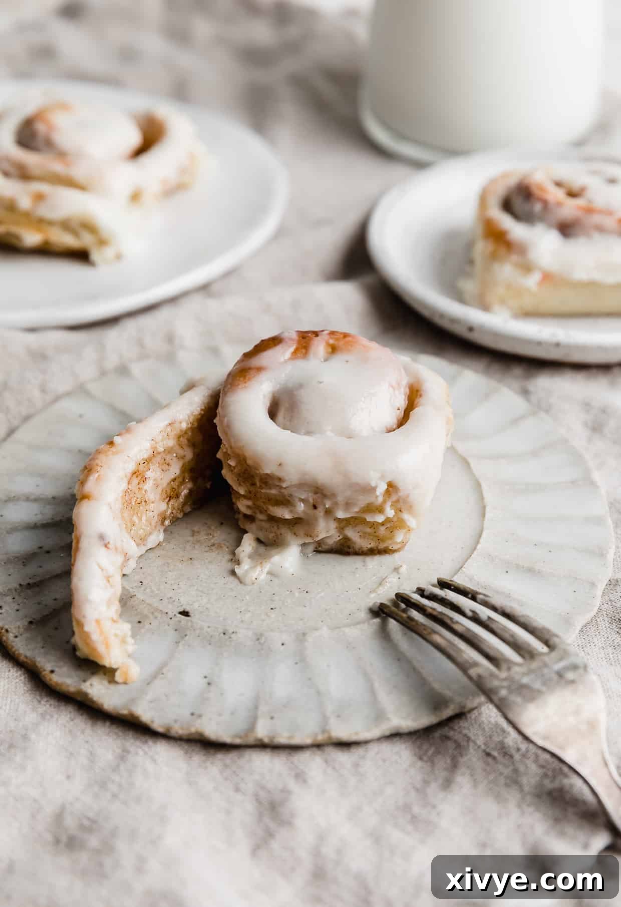 Irresistible Mini Cinnies 21 A mini cinnamon roll on a white plate with its spiral unfurling, showcasing the delicious layers of cinnamon sugar.
