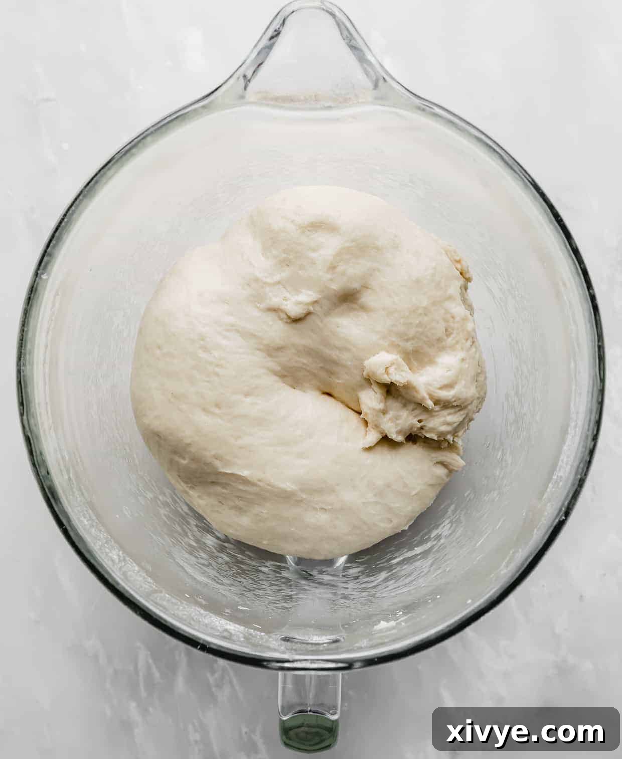 Irresistible Mini Cinnies 9 Mini Cinnamon Roll dough in a glass bowl after resting, showing a slight puffing up.