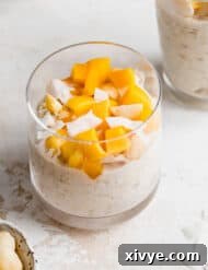 A glass cup full of Mango Overnight Oats topped with fresh diced mango, presenting a vibrant and inviting breakfast.