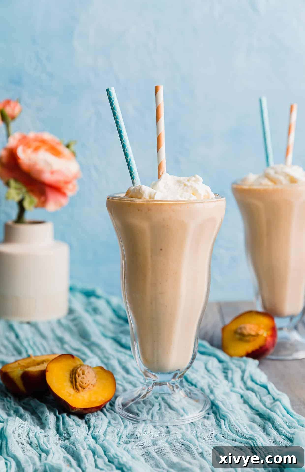 Perfect Peach Milkshake Inspired by Chick-fil-A 2 Two glasses of peach milkshake against a blue background.