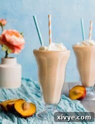 Two glasses of peach milkshake against a blue background.