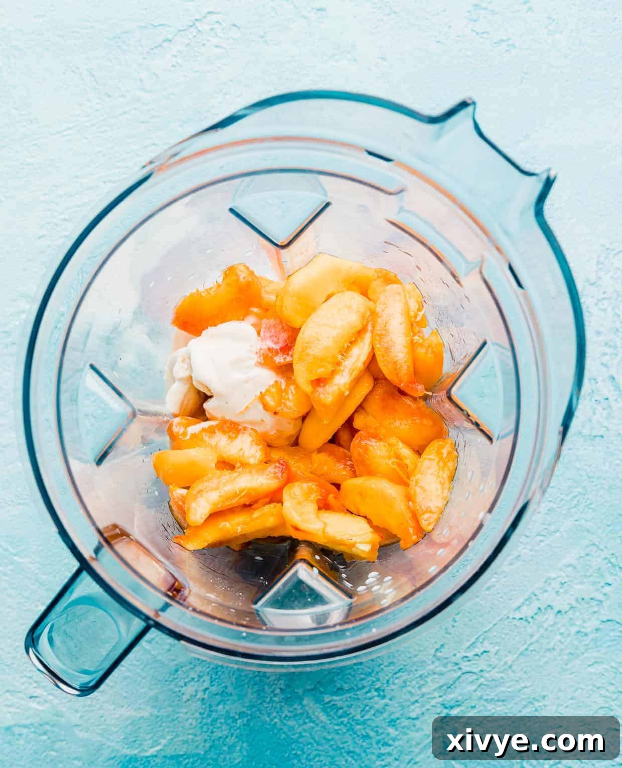 Perfect Peach Milkshake Inspired by Chick-fil-A 4 sliced peaches, ice cream, and milk in a blender on a blue background.