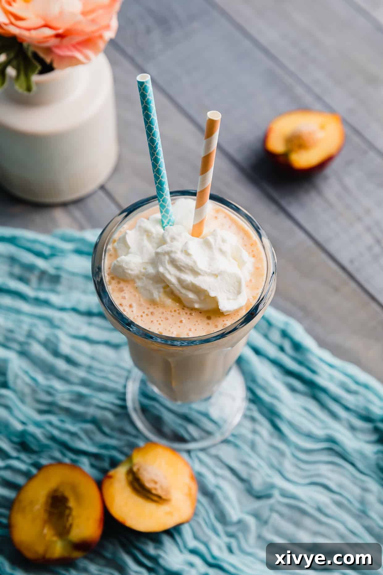 Perfect Peach Milkshake Inspired by Chick-fil-A 6 A Peach Milkshake on a blue napkin with two straws in the glass.