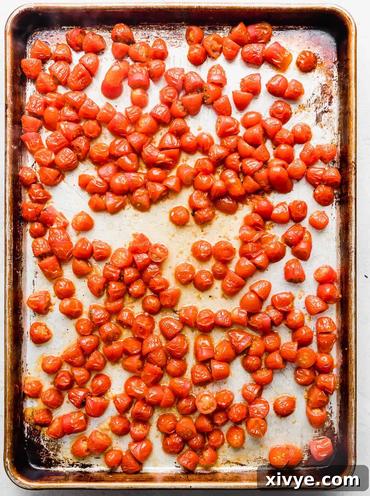 Shriveled roasted red tomatoes on a baking sheet.