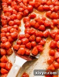 Roasted grape tomatoes on a baking sheet.