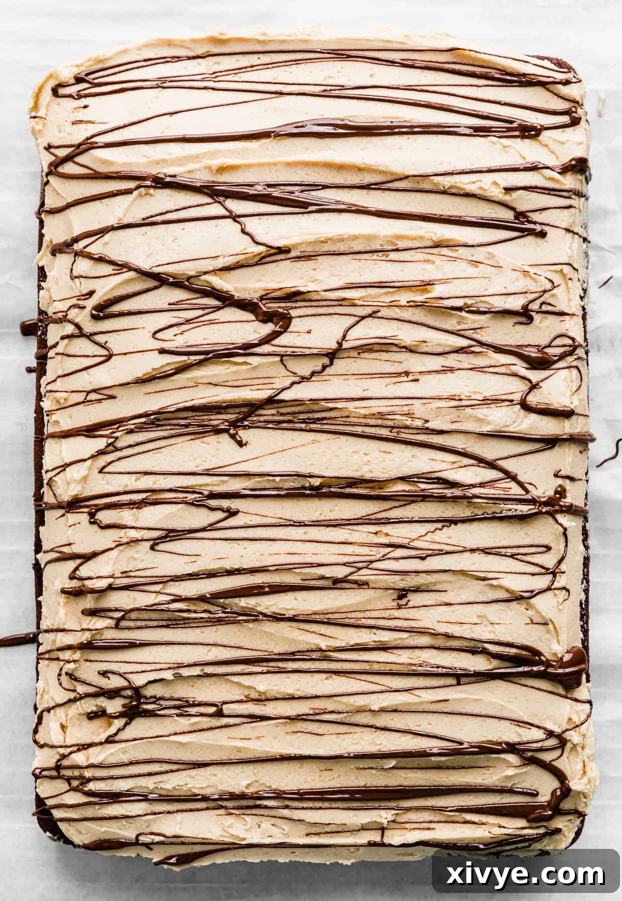 Melted chocolate drizzled overtop of a Chocolate Cake with Peanut Butter Frosting.