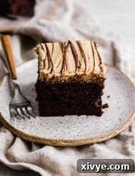 A slice of square chocolate cake topped with a peanut butter frosting and drizzled with melted chocolate.