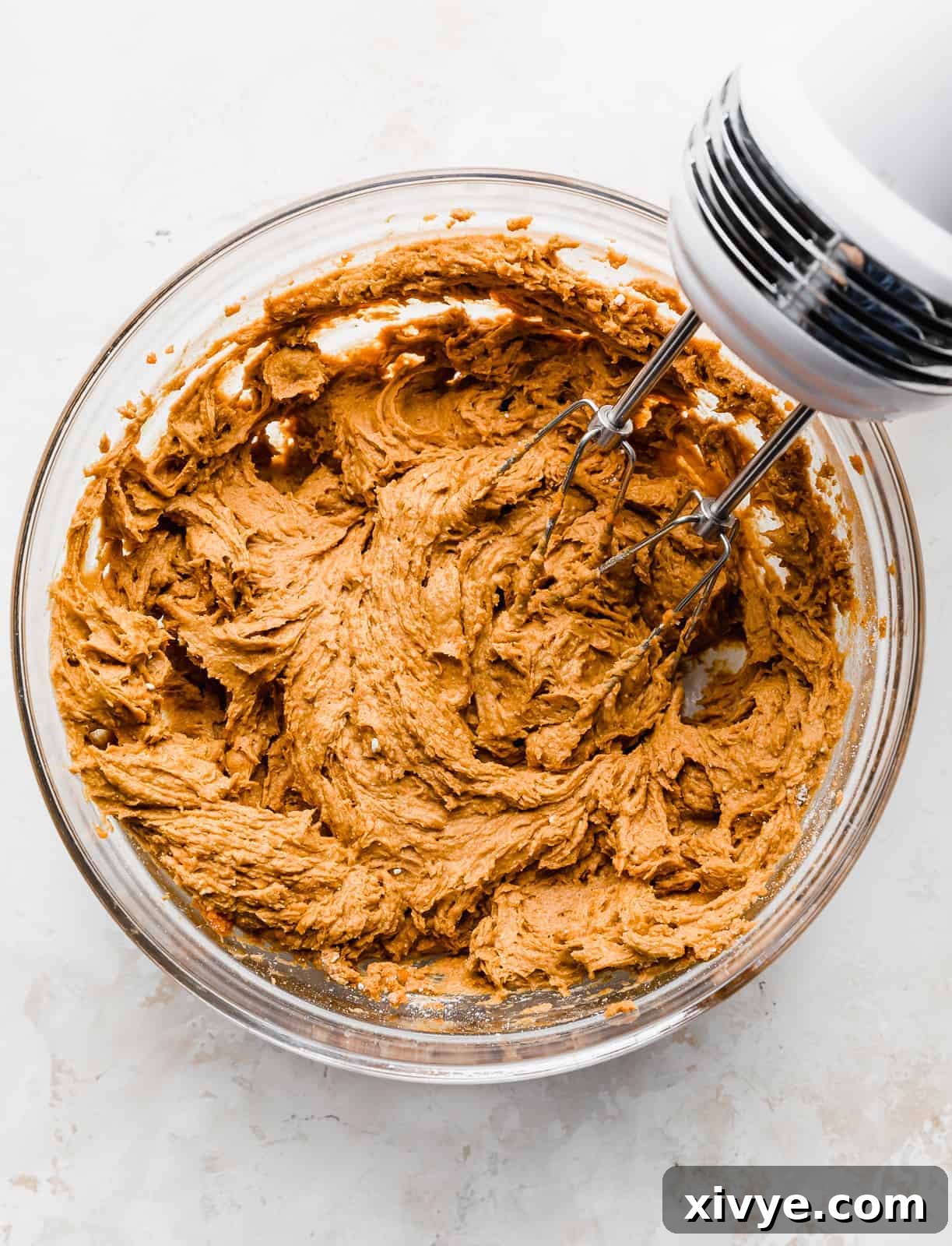 A hand mixer beating a 2 Ingredient Pumpkin Muffin batter in a bowl, showing the thick consistency.