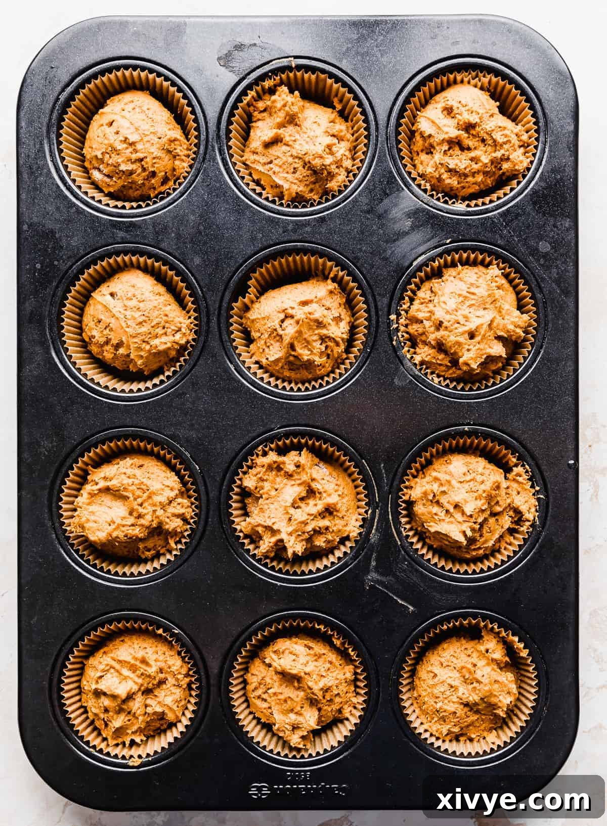 2 Ingredient Pumpkin Muffin batter in a lined muffin tin, ready for the oven.