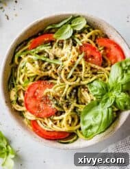 Sun-Kissed Zucchini Pasta 8 Zucchetti Pasta in a white bowl with nutritional yeast, tomatoes, and fresh basil.