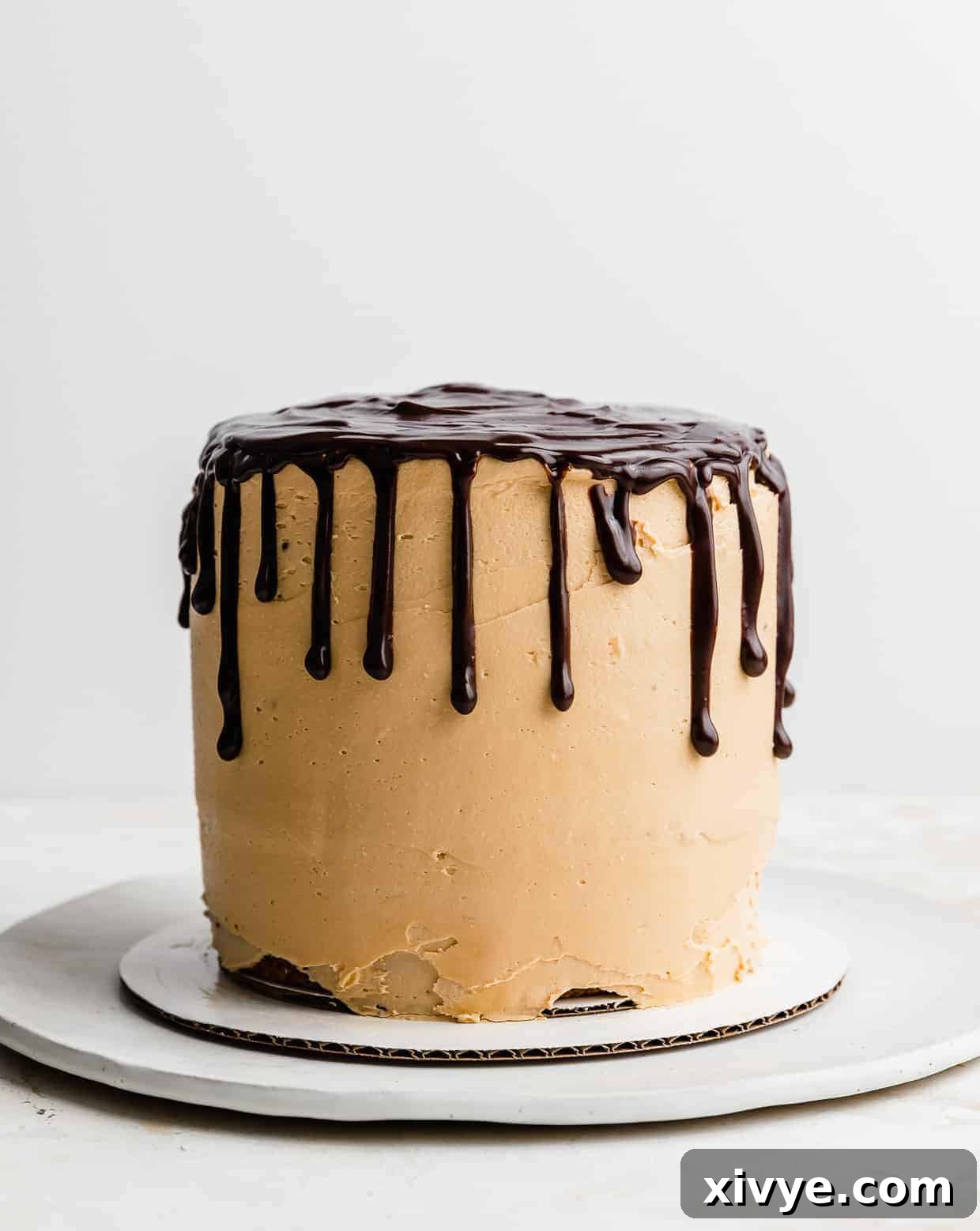 A beautifully decorated 7 Layer Bar Cake, generously covered in smooth butterscotch buttercream, with an artistic chocolate ganache drip cascading down its sides.
