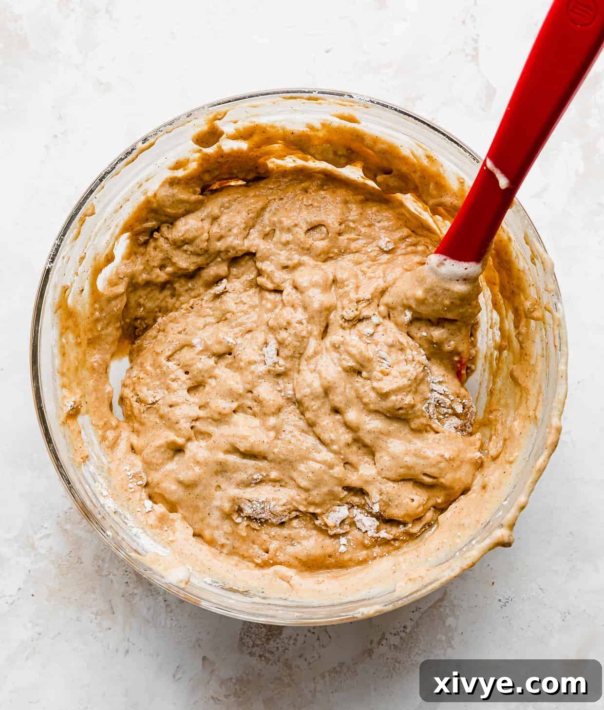 Smooth, evenly mixed pumpkin pancake batter in a transparent glass bowl, showcasing its rich orange hue and ready for the next step of adding chocolate chips.