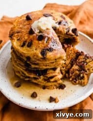 Pumpkin Chocolate Chip Pancakes on a white plate with a wedge of pancake cut out.