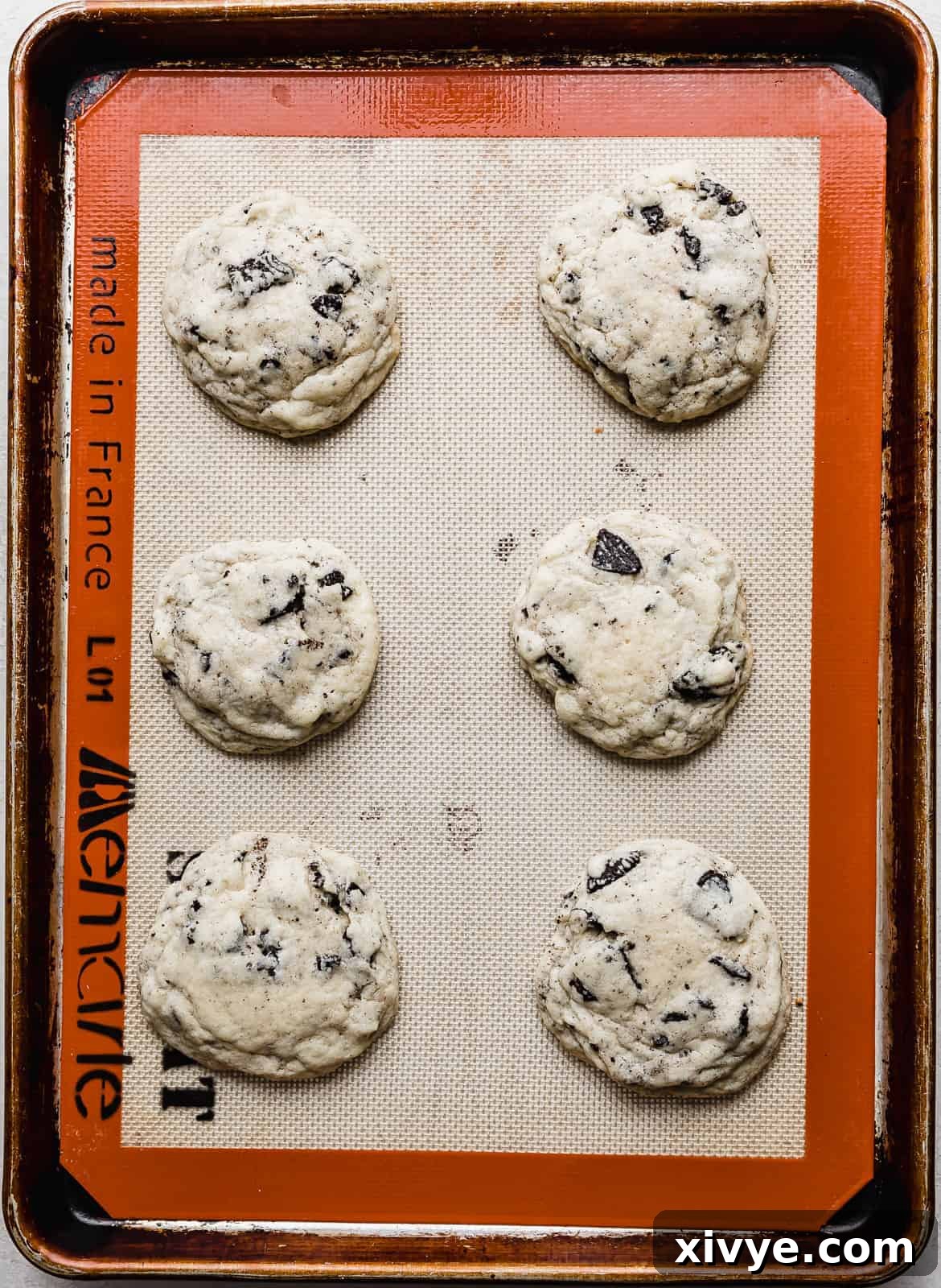 Six freshly baked cookies and cream milkshake cookies, golden at the edges, resting on a baking sheet, perfectly cooled and ready for frosting.