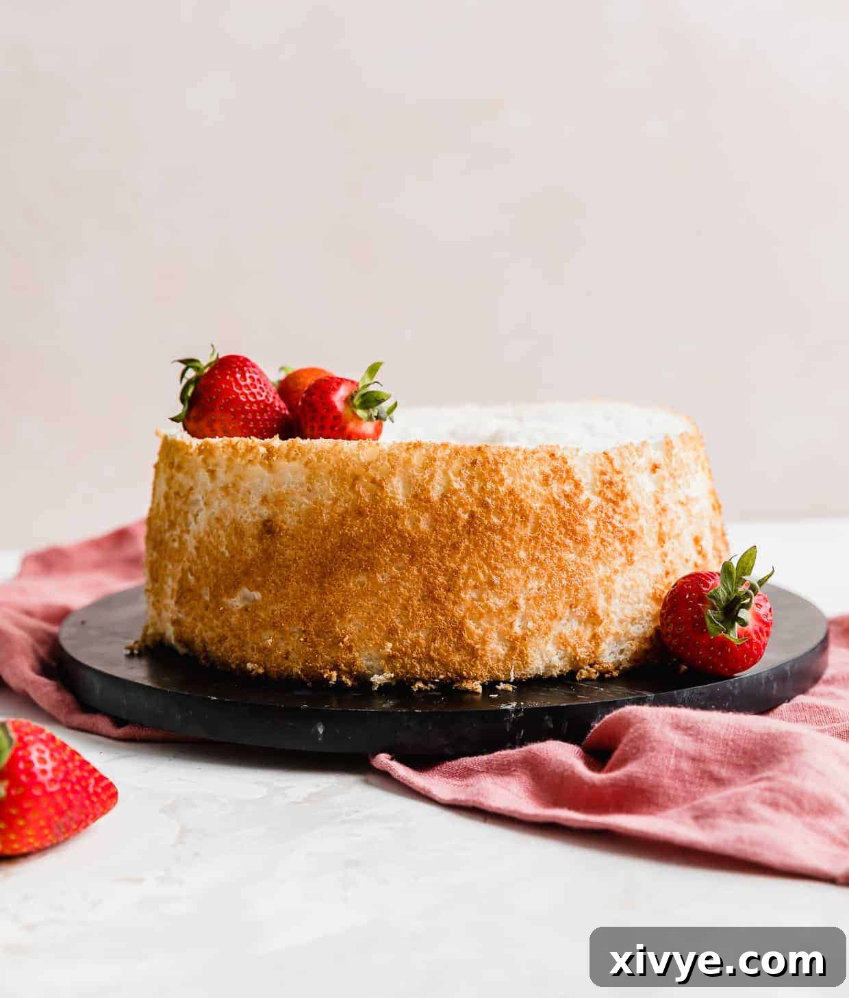 An exquisitely baked angel food cake resting gracefully on a sleek black round platter, ready to be served.