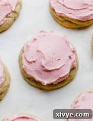 Perfect Crumbl Pink Sugar Cookie Recipe 11 A Copycat crumbl sugar cookie topped with pink frosting on a white background.