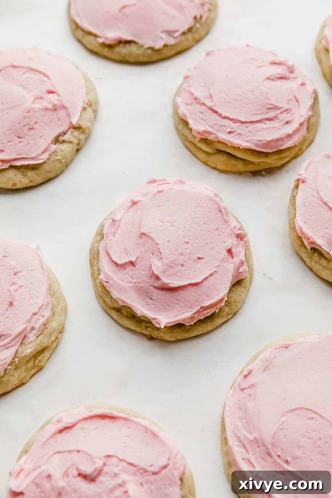 Perfect Crumbl Pink Sugar Cookie Recipe 3 A perfectly baked, round copycat Crumbl sugar cookie with a thick layer of pink almond frosting on a bright white background, showcasing its delightful texture.