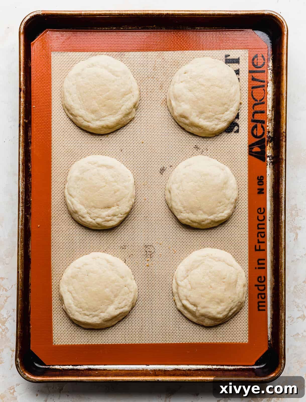 Perfect Crumbl Pink Sugar Cookie Recipe 7 Six freshly baked sugar cookies with slightly golden edges and soft centers cooling on a baking sheet.