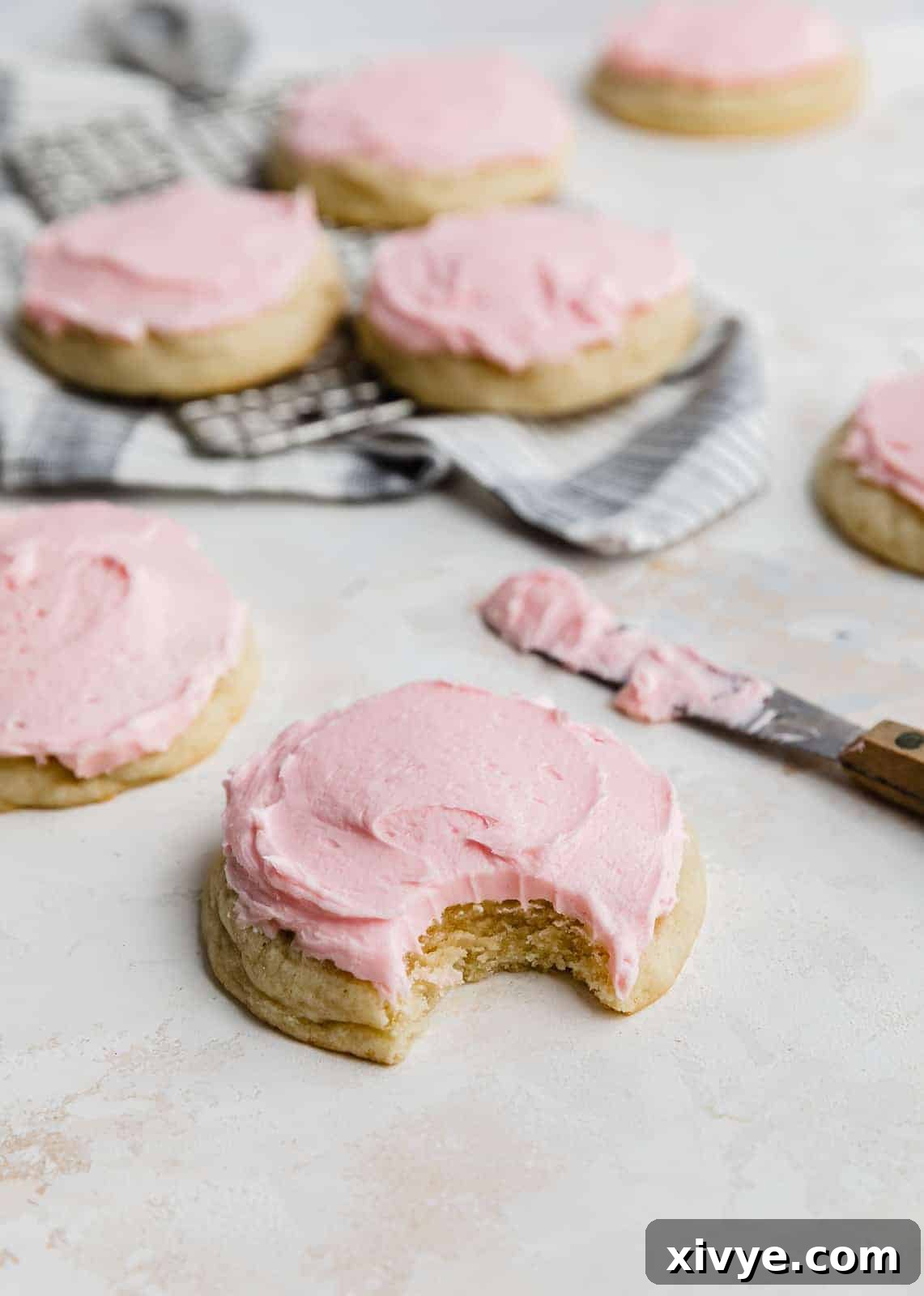 Perfect Crumbl Pink Sugar Cookie Recipe 10 A delicious copycat Crumbl Sugar Cookie with a bite taken out, showing its soft interior and the rich pink frosting, on a white background.