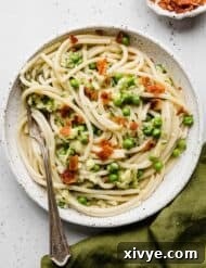 Pasta with Zucchini Sauce topped with chopped bacon on a white plate, ready to be served.