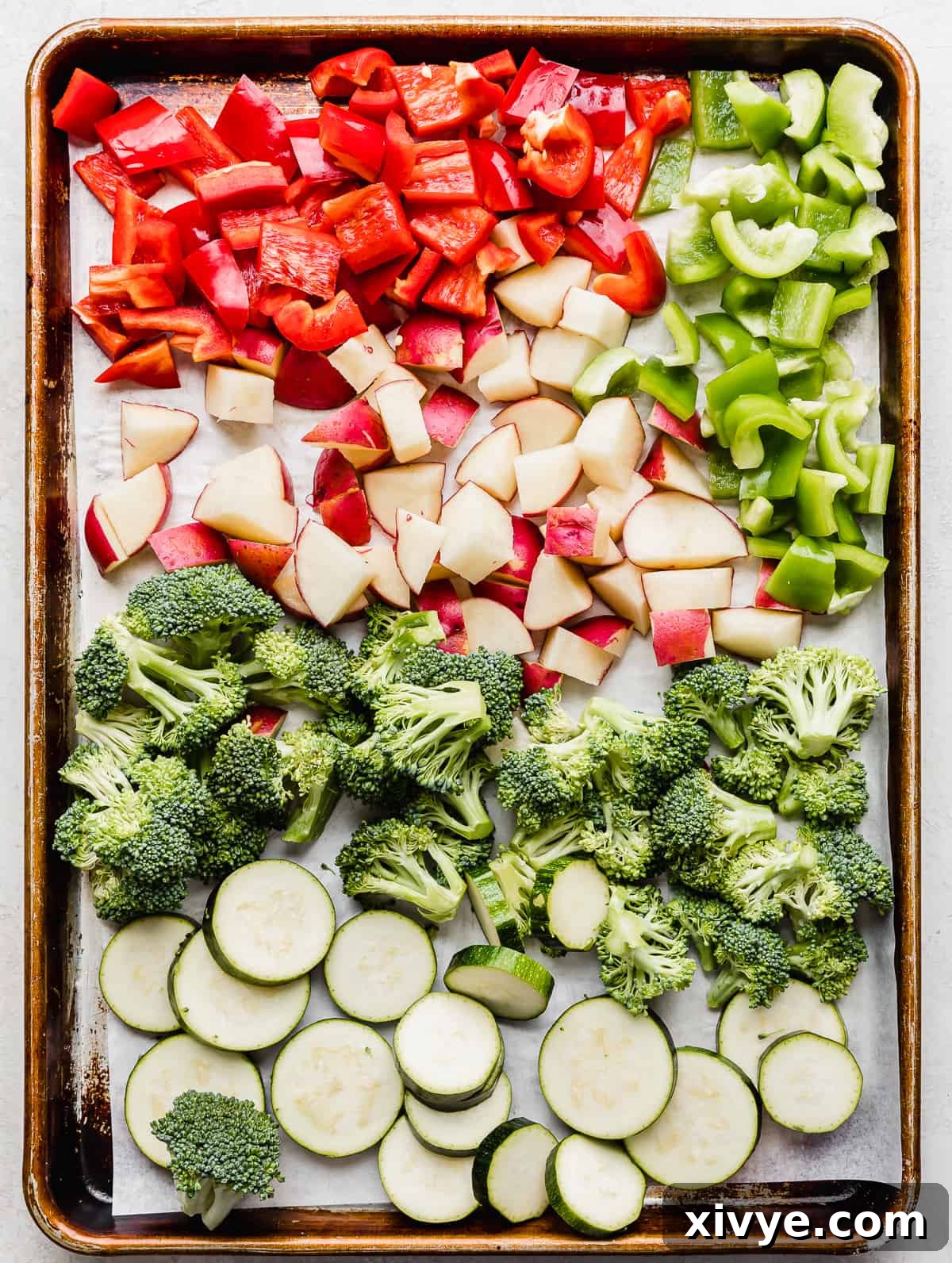 One-Pan Italian Sausage and Roasted Vegetables 4 A baking sheet with red and green peppers, cut potatoes, broccoli florets and coin zucchini slices.