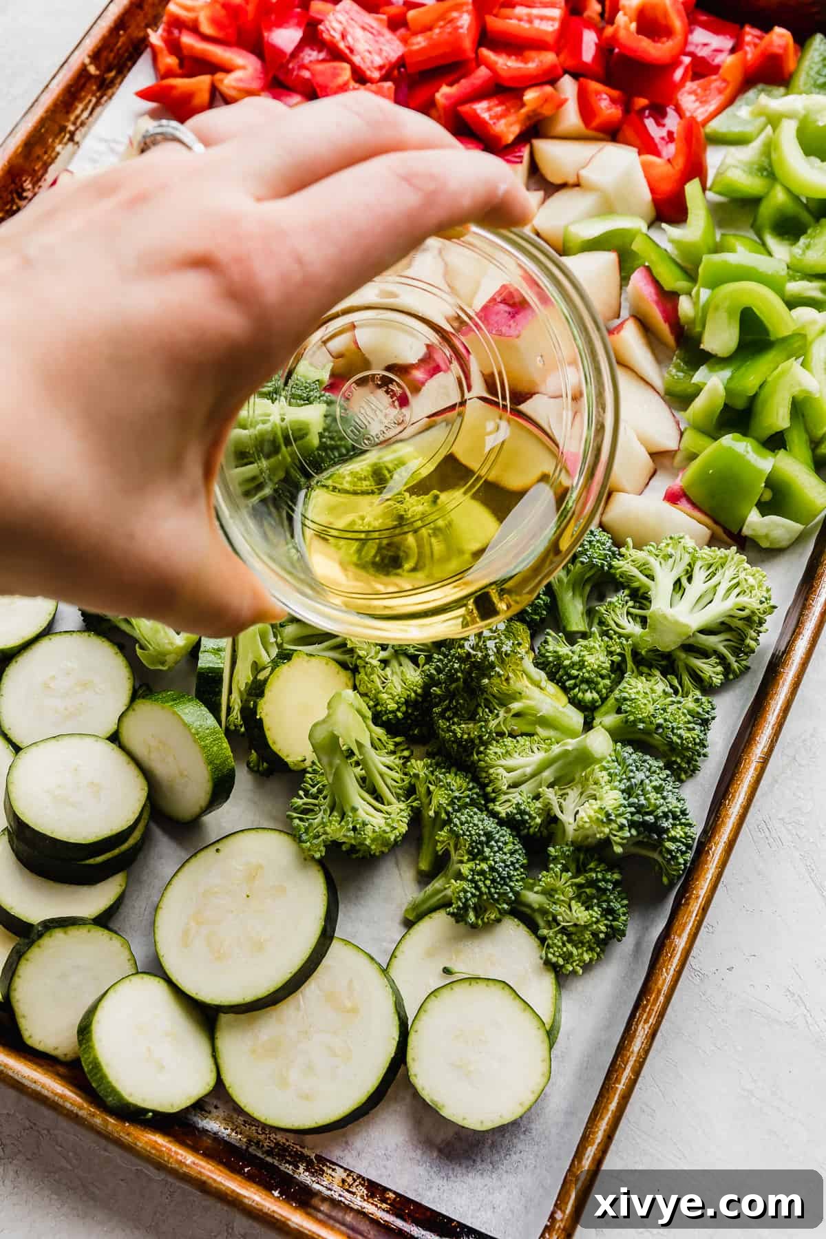 One-Pan Italian Sausage and Roasted Vegetables 5 Olive oil being poured over Sheet Pan Sausage and Veggies.