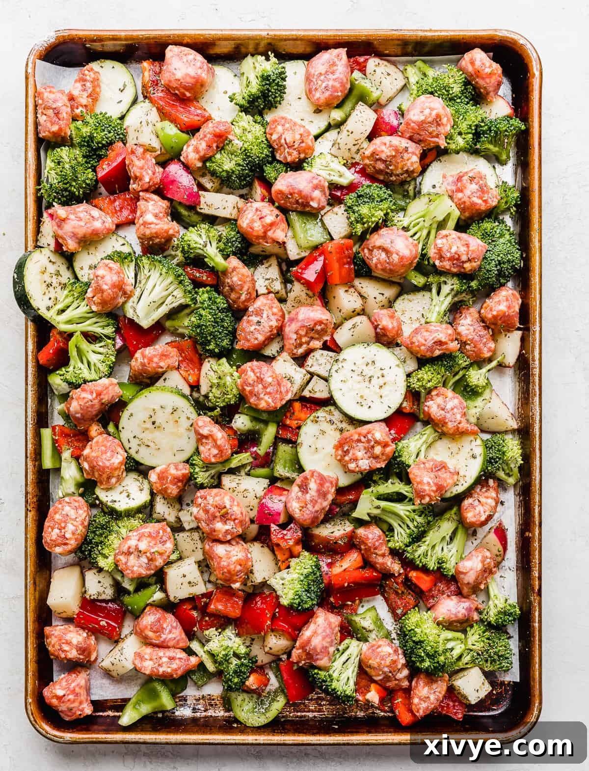 One-Pan Italian Sausage and Roasted Vegetables 6 Unbaked Italian sausage and chopped veggies on a baking sheet.