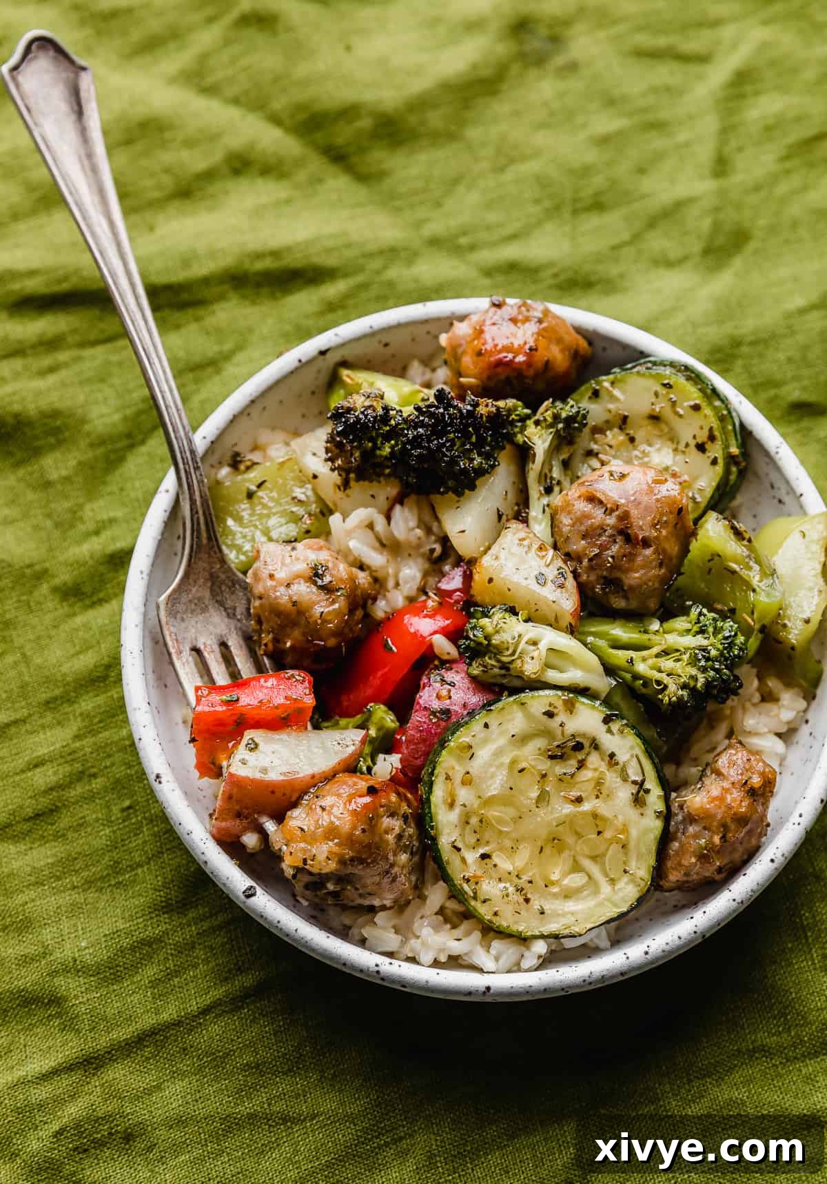 One-Pan Italian Sausage and Roasted Vegetables 9 A white plate full of Sheet Pan Sausage and Veggies, on a green linen napkin.
