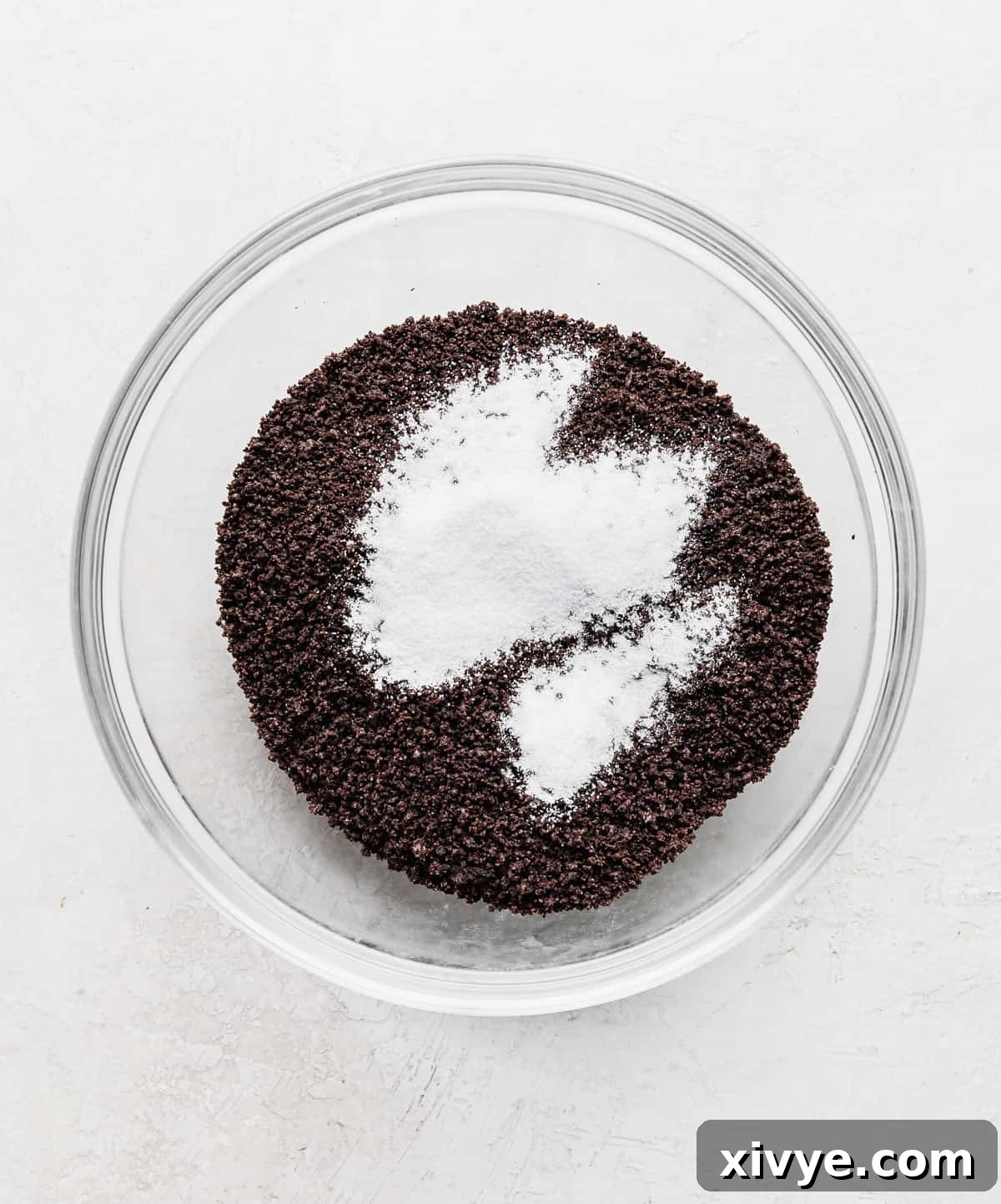 Irresistible Oreo Pie Crust 5 Crushed Oreo crumbs and white sugar in a glass bowl.