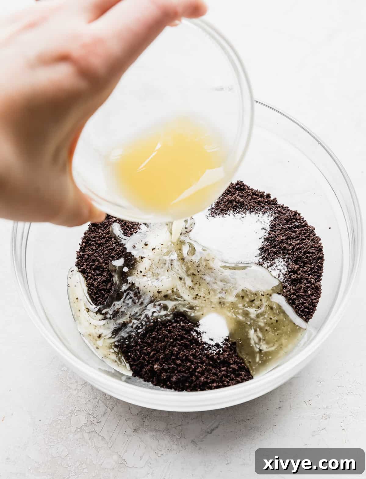 Irresistible Oreo Pie Crust 6 Melted butter being poured into a bowl full of crushed Oreo crumbs and sugar.