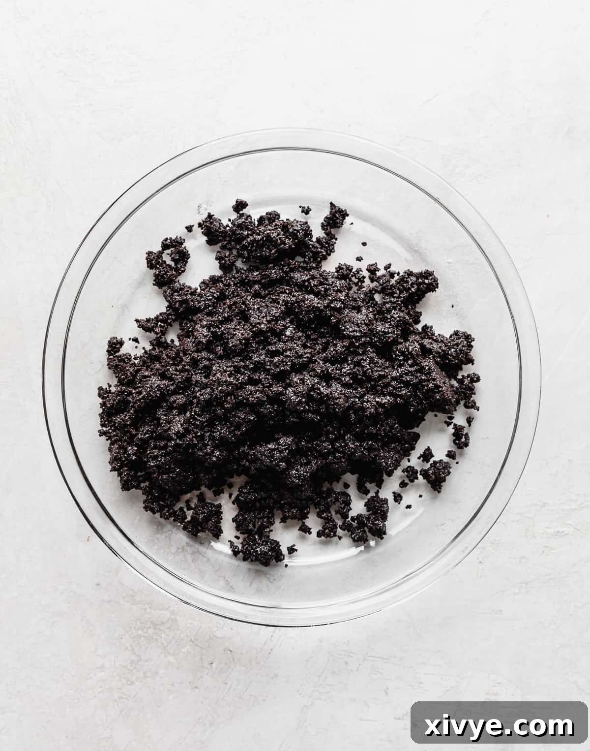 Irresistible Oreo Pie Crust 7 A glass pie dish with Oreo crumbs in it for making Oreo Pie Crust.