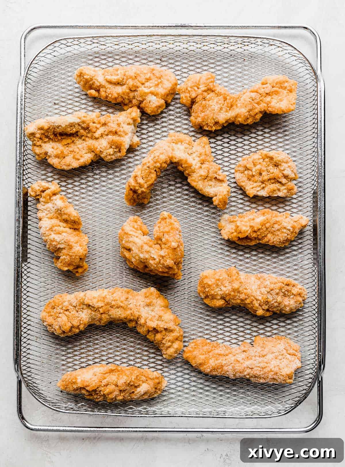 Frozen chicken tenders neatly arranged on a wire air fryer rack, ready for cooking.