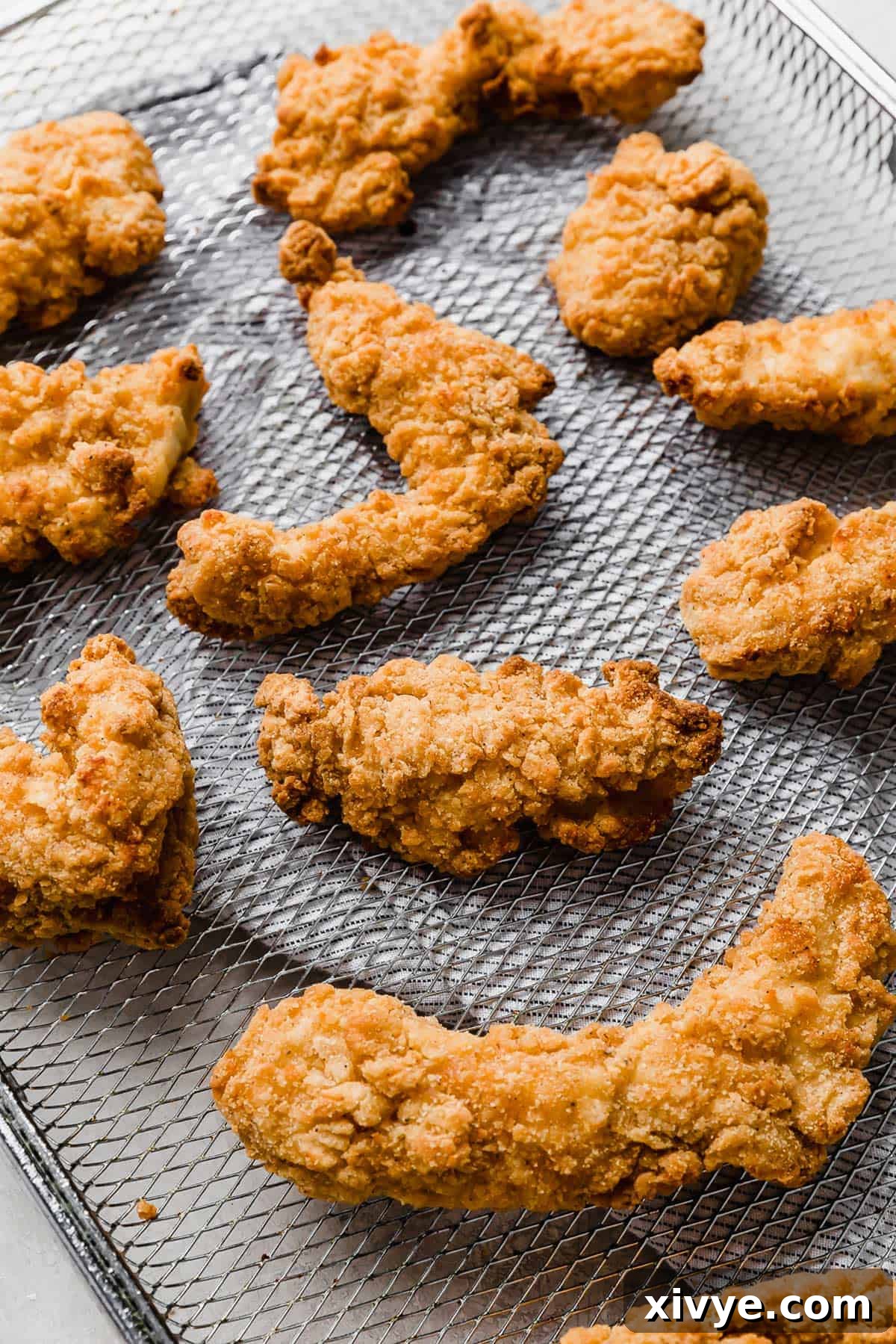 Freshly cooked, golden crispy Air Fryer Frozen Chicken Tenders cooling on a wire rack.