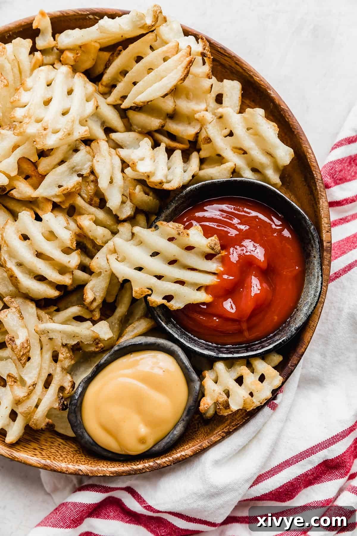 Crispy Waffle Fries from Your Air Fryer 2 Perfectly golden, crispy air fryer waffle fries served on a plate with various dipping sauces.