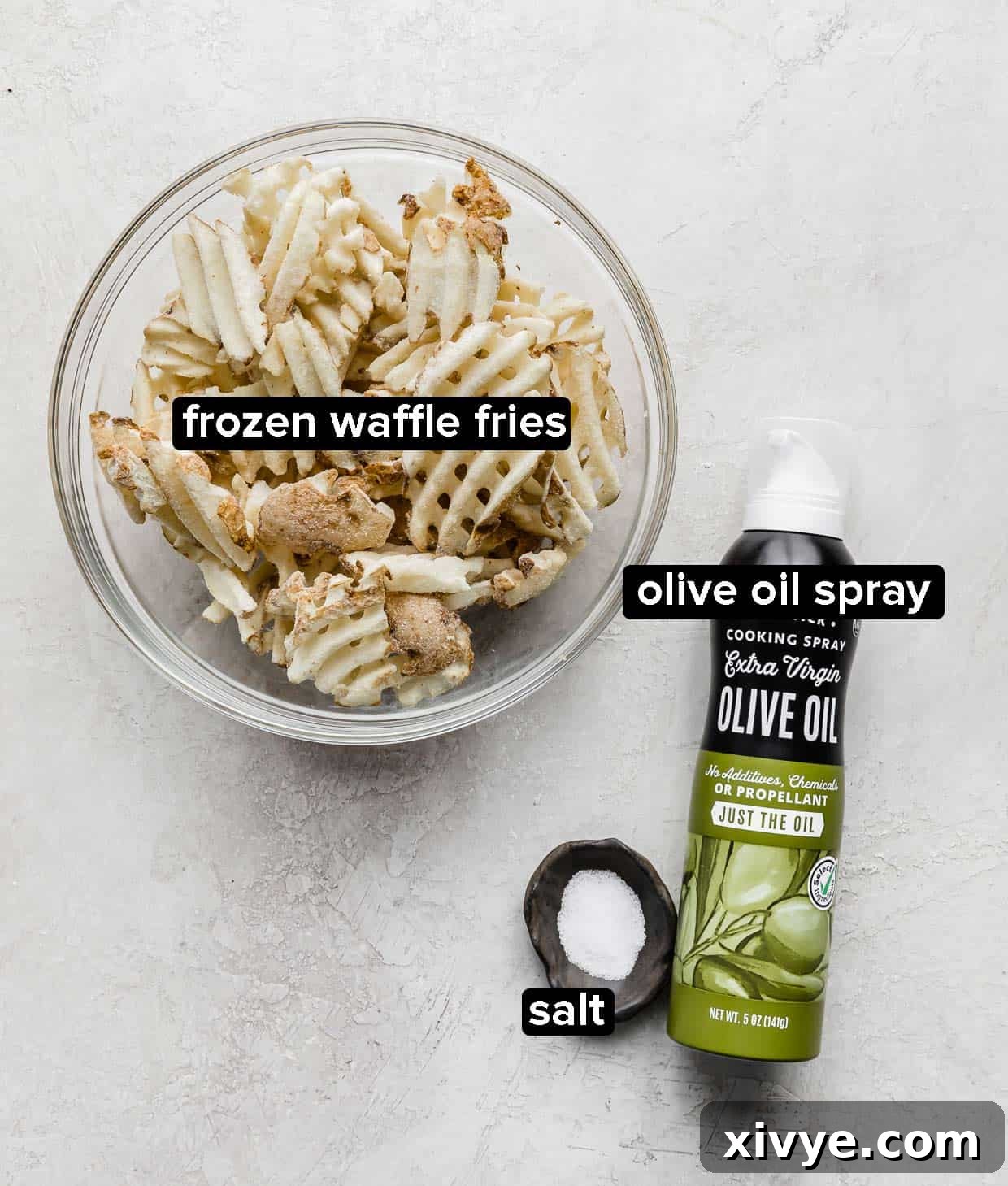 Crispy Waffle Fries from Your Air Fryer 3 Frozen waffle fries in a glass bowl with a bowl of salt and olive oil spray next to the bowl.