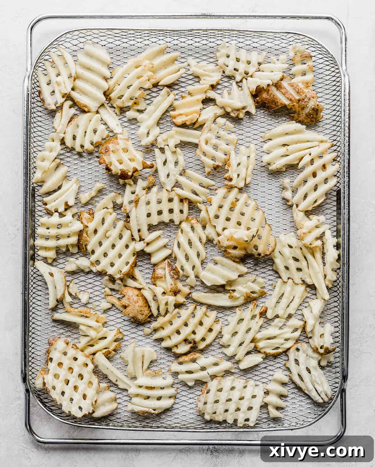 Crispy Waffle Fries from Your Air Fryer 4 A wire air fryer rack with frozen waffle fries on it.