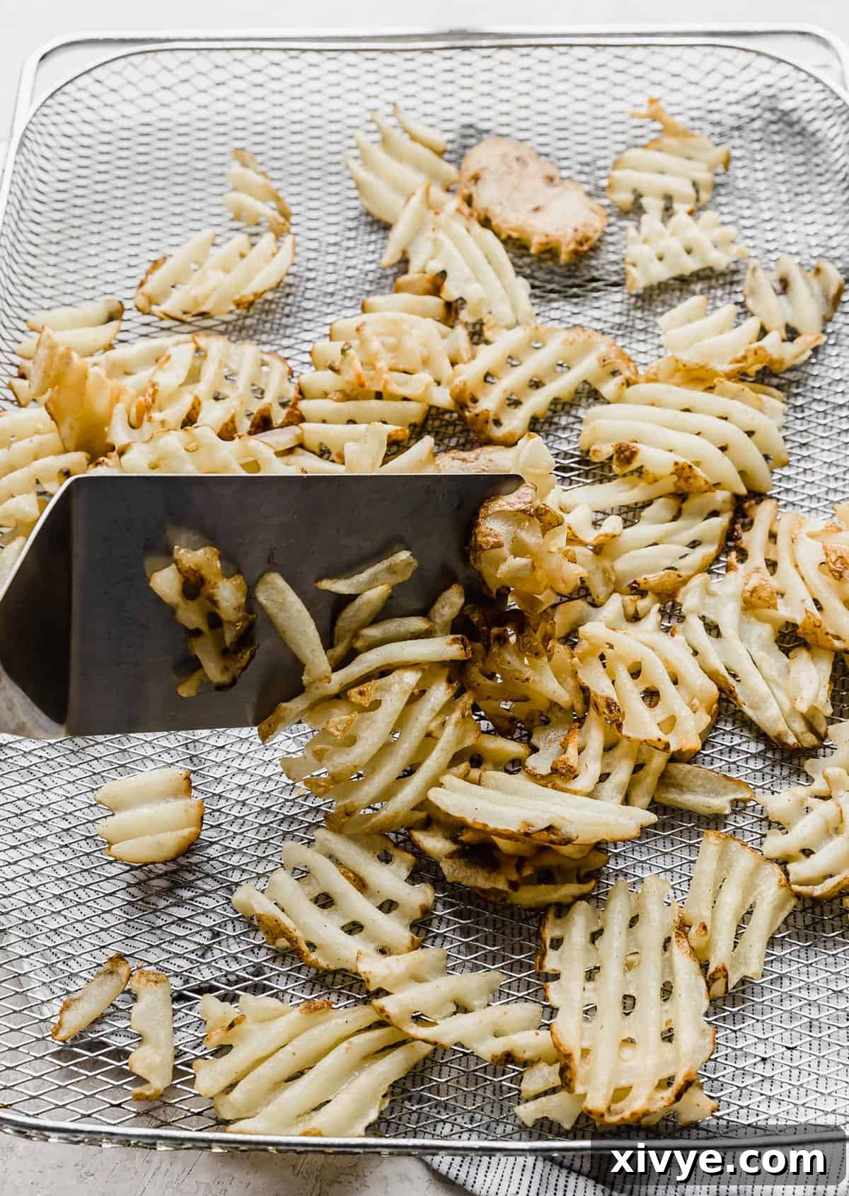 Crispy Waffle Fries from Your Air Fryer 5 Air fryer basket filled with waffle fries, halfway cooked and being tossed.