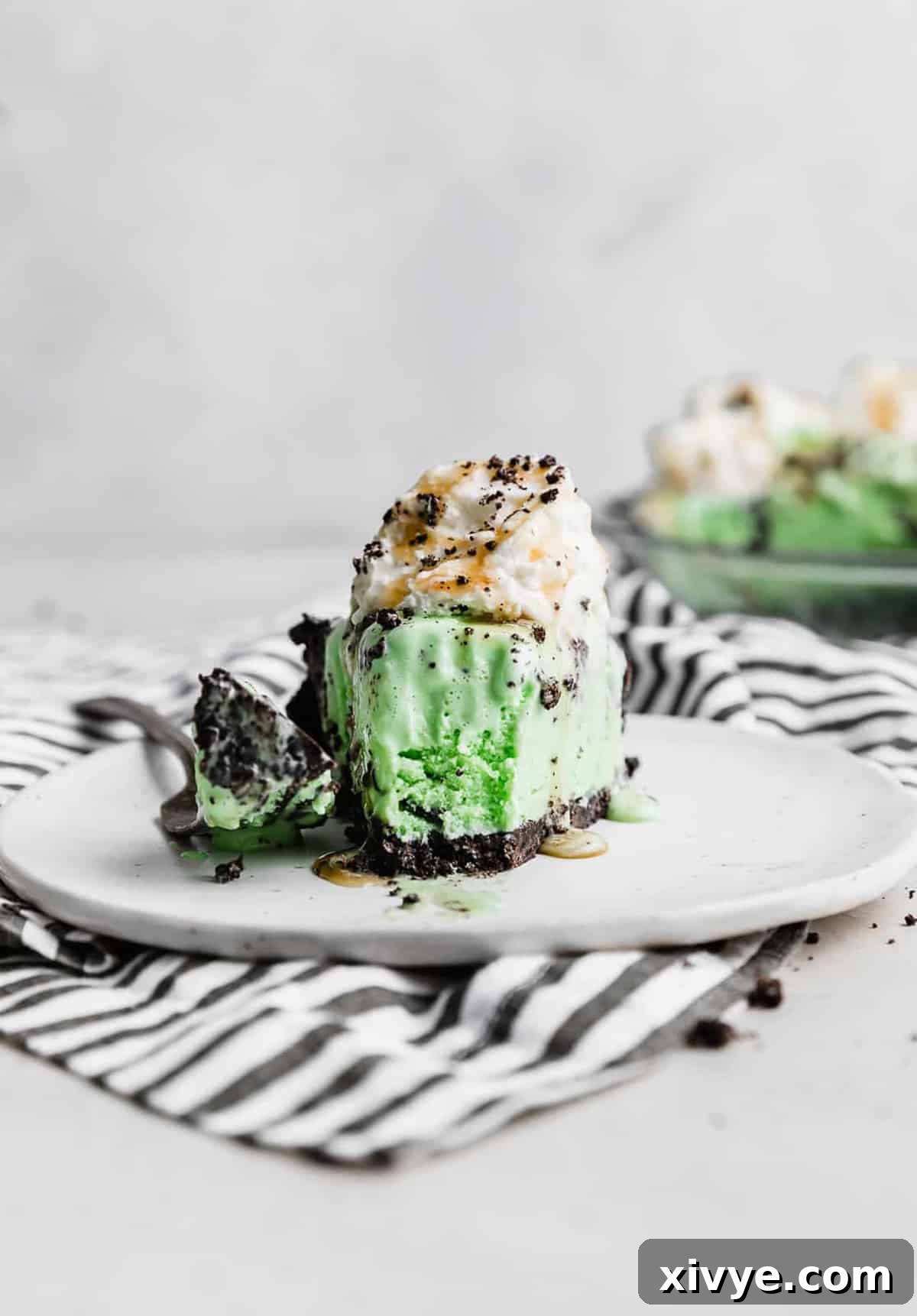 Concrete Crumble 8 A delightful slice of Asphalt Pie on a plate, with a fork taking a bite, showing the creamy mint ice cream and crunchy Oreo crust.